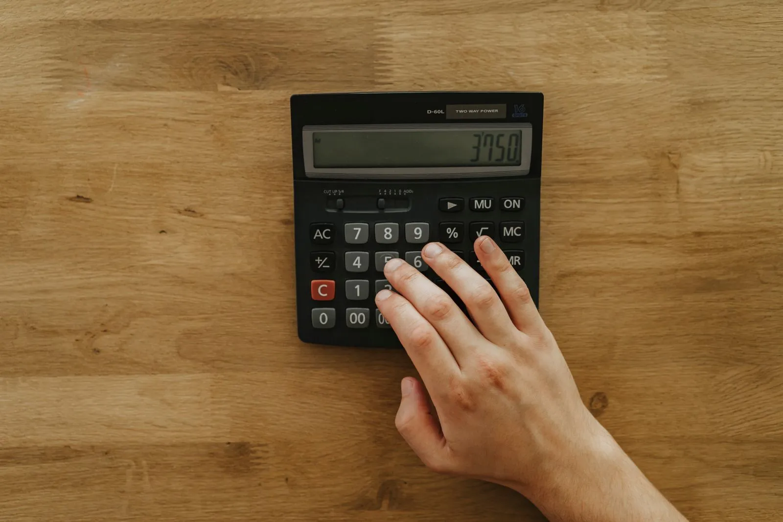 Calculatrice, plan d'appartement et tableau de loyers posés sur un bureau en bois clair